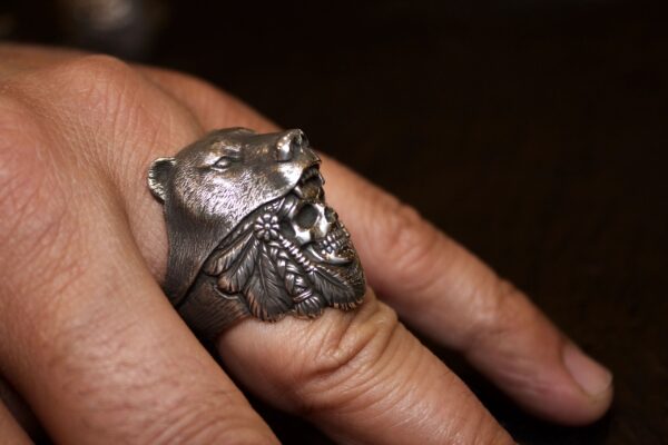 A silver ring featuring a detailed lion's head worn on a finger.