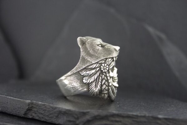 Artistic silver ring shaped like a bear's head with engraved feathers.