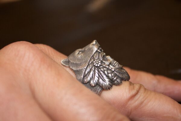 A silver ring shaped like a detailed wolf's head on a finger.