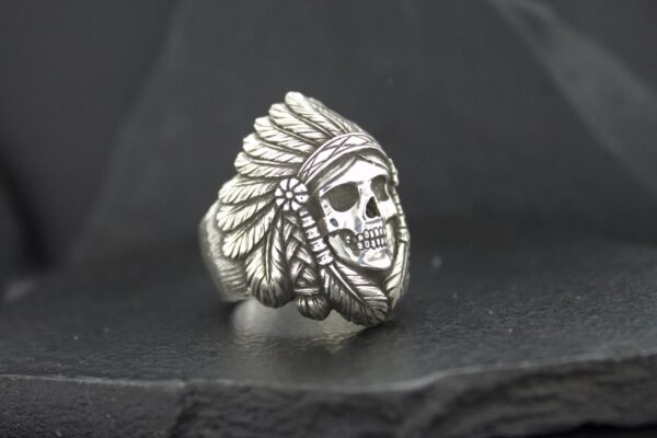 A silver ring featuring a skull wearing a Native American headdress.