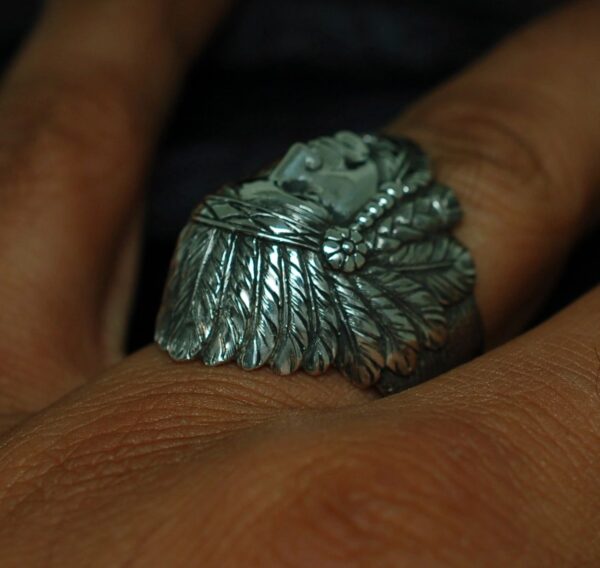 Close-up of a silver ring shaped like a wing on a finger.