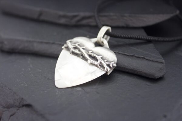Silver pendant shaped like an arrowhead with a barbed wire design.