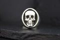 Silver ring with a detailed skull design on a black background.