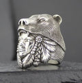 A detailed silver ring featuring a bear head and Native American chief design.