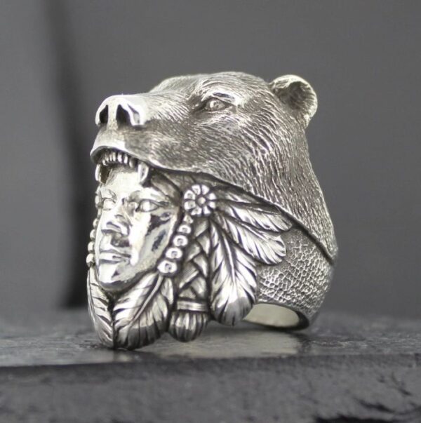 A detailed silver ring featuring a bear head and Native American chief design.