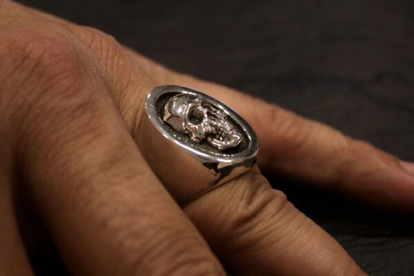 Close-up of a hand wearing a detailed silver skull ring.