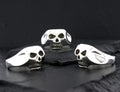Three skull-shaped objects with black and white patterns on a black surface.