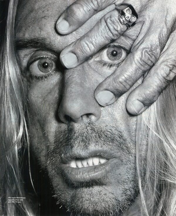 Close-up of a man with intense eyes framed by his tattooed hands.