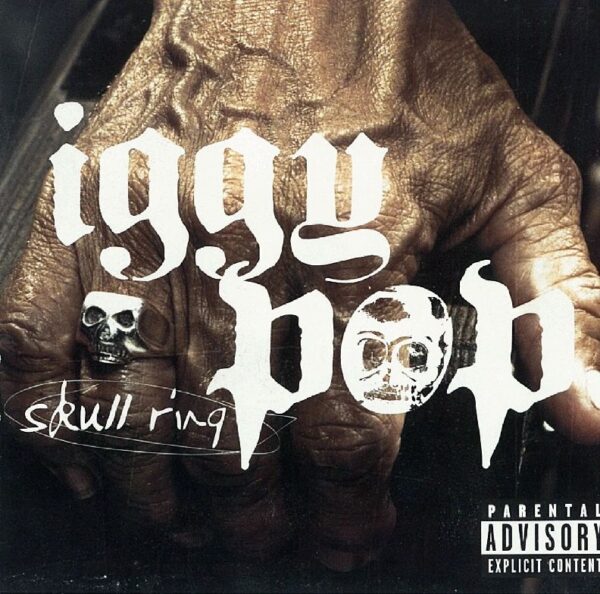 Close-up of a hand with a skull ring and 'iggy pop' text.