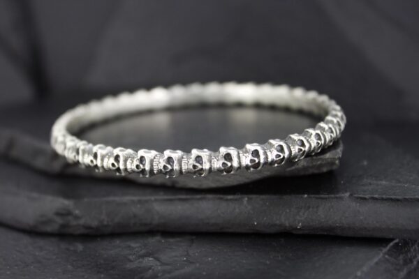 Close-up of a shiny silver bracelet on a dark surface.