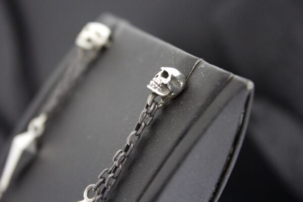 Close-up of a silver skull charm on a chain.