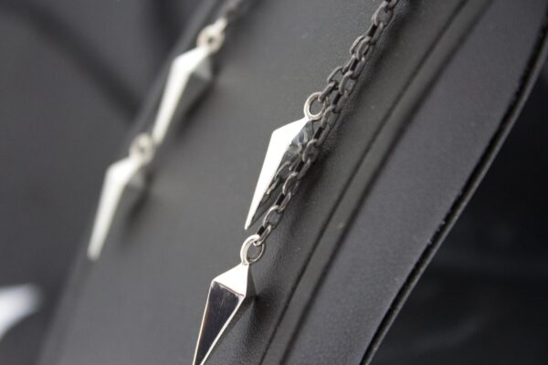 Close-up of silver geometric pendant necklace on black fabric.