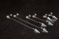 Silver chain earrings with geometric pendants on a dark surface.