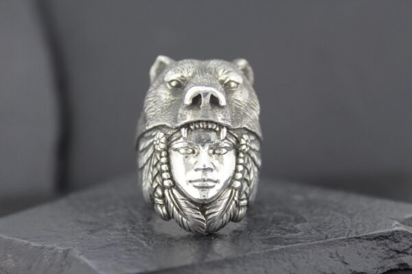Intricately carved ring featuring a human face and a bear head.