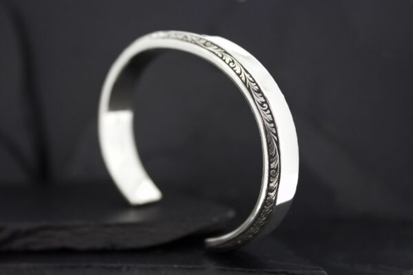 Elegant silver cuff bracelet with intricate engraving.