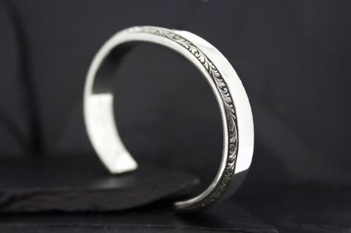 Elegant silver cuff bracelet with intricate engraving.