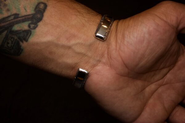 Close-up of a wrist wearing a silver bracelet with a tattoo nearby.
