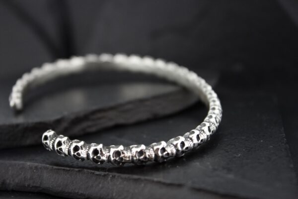Close-up of a silver beaded bracelet on a dark surface.