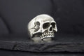 A silver skull ring with detailed cracks and hollow eyes.