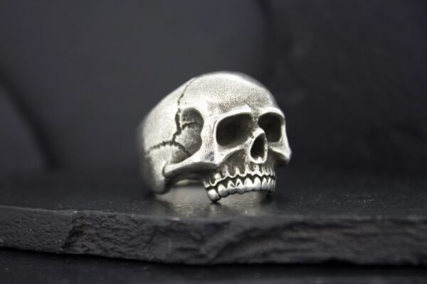 A silver skull ring with detailed cracks and hollow eyes.