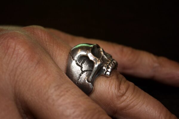 A silver skull-shaped ring worn on a finger.