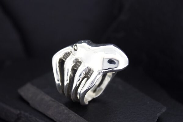A sleek silver ring shaped like a skeletal hand on black background.