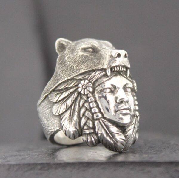 A silver ring featuring a bear and Native American chief design.