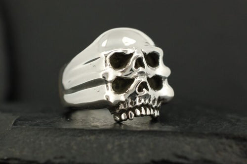 Silver ring with two stacked skull designs.