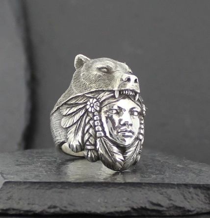 A silver ring featuring a bear head and a Native American chief face.