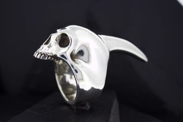 A silver ring shaped like a skull with a curved horn.