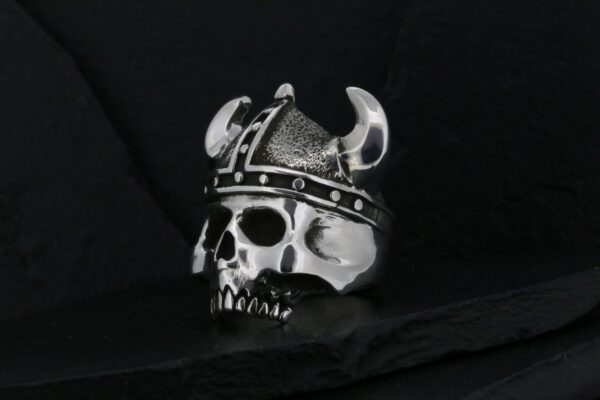 A skull wearing a Viking helmet with horns and rivets.