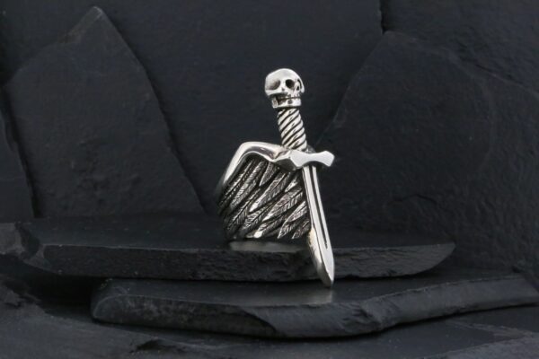Silver skull and sword ring with intricate wing design.