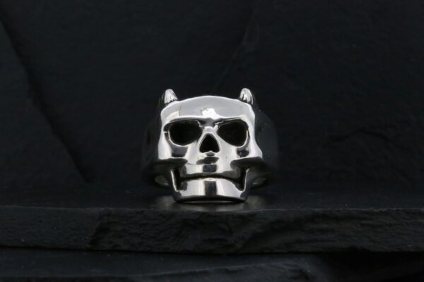 A metallic skull ring with a dark background.