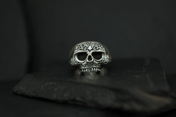 Intricately designed silver skull ring with floral patterns.