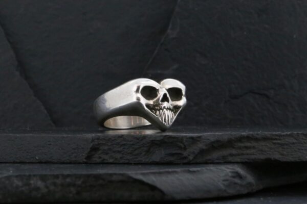 A silver ring shaped like a skull with heart-like features.