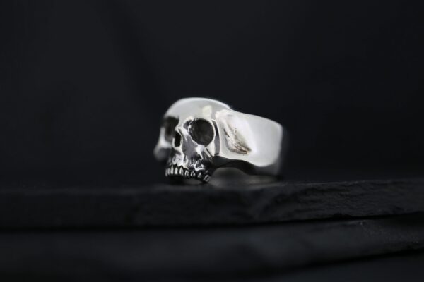 A silver skull-shaped ring on a dark surface.