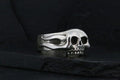 Silver skull ring with detailed design on black background.