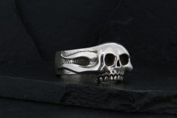 Silver skull ring with detailed design on black background.