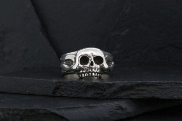 A silver skull ring with detailed teeth design.