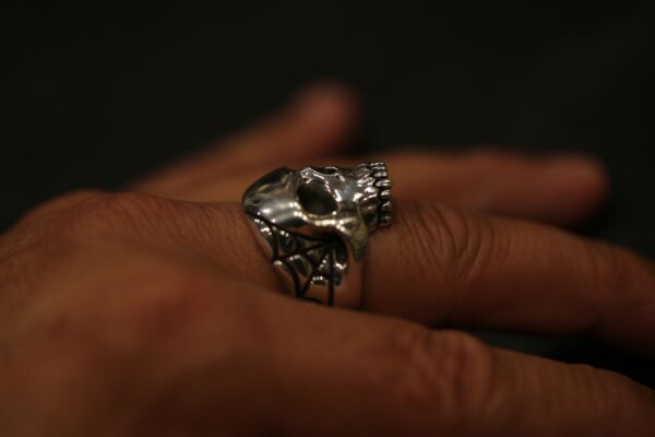Close-up of a hand wearing a detailed silver skull ring.