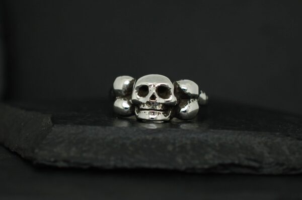 Silver skull ring with a dark background.
