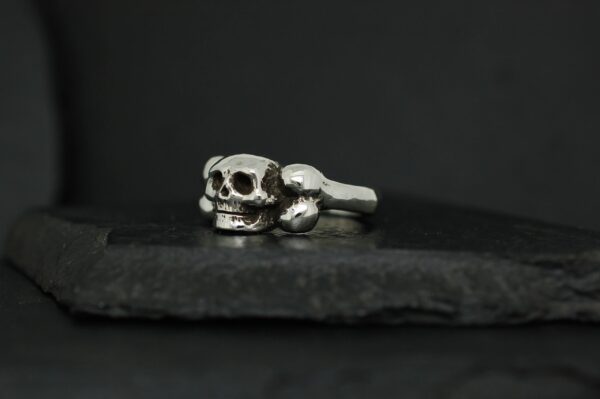 Silver skull ring on a dark surface.