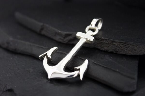 A shiny silver anchor pendant on a black cord.