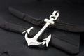 A shiny silver anchor pendant on a black cord.