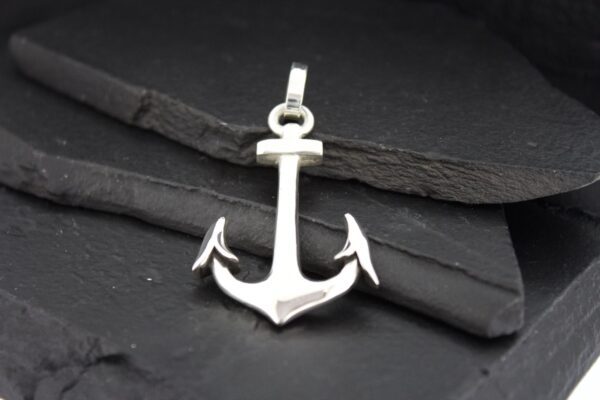 Silver anchor pendant on a dark background.