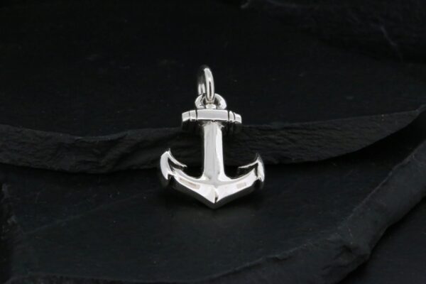 A shiny silver anchor pendant on a dark background.