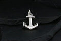 A shiny silver anchor pendant on a dark background.