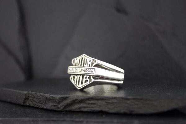 Silver ring featuring the Harley-Davidson logo on a dark background.