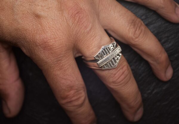 Hand wearing a silver ring with engraved text.