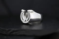 A silver ring featuring a horseshoe design on a black background.